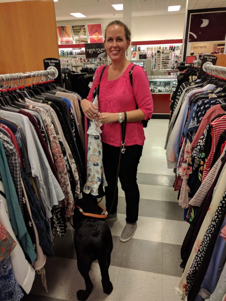 Picture of Adrianne and Robin shopping at TJ Mass. Adrianne is smiling at the camera and Robins back is toward me with her head burried underneath the rack of clothing.