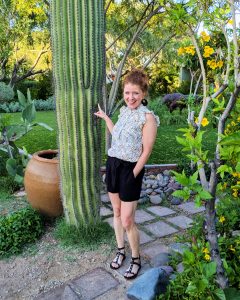 I am standing beside a huge cactus in AZ weaing my floral top and black tie waist shorts and gladiator sandals